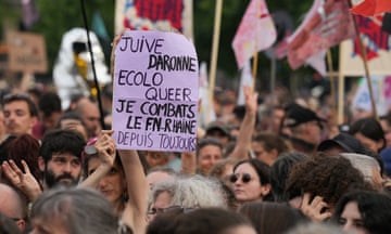 A demonstrator in a crowd holds up a placard reading: 'Juive, daronne, ecolo, queer. Je combats le FN-R-Haine depuis toujours'