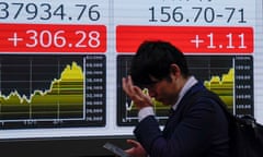 A pedestrian walks past a display showing the foreign exchange rate between Japanese yen and US dollar.