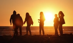 Six young people in silhouette at Polzeath beach at sunset: the beach has become a magnet for privileged young people to party into the night.