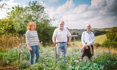 Georgina Walton, in jeans, and Nick Walton with his hand on a garden tool stand next to Stephen Buck in a Somerset field