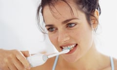 woman brushing teeth with electric toothbrush