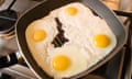 Eggs frying in a pan on a gas hob