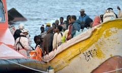 Migrants in a boat in the Mediterranean with coastguards