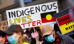 A woman wearing a facemask is seen holding an indigenous lives matter placard during a Black Lives Matter rally in Melbourne, Australia