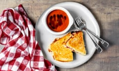 Bowl of tomato soup with grilled cheese sandwich on a plate on wooden background<br>GettyImages-1371337733