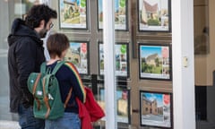 a couple look through an estate agent window