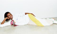 Leomie Anderson lying down, wearing white outfit.