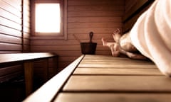Man in towel lounges on wood surface of indoor sauna<br>Sauna, relax in Lapland, Finland