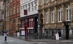A pedestrian walks past the empty tables of pubs and restaurants in Liverpool