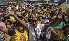 A crowd of people, many wearing the ANC's colours of yellow and green, attend a march. Some hold their hands out while others hold placards