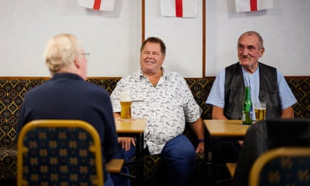 Three men sitting chatting around pints of beer