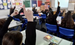 Pupils raise their hands in a lesson