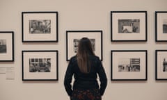 Ella Murtha stands with her back to the camera as she looks at prints of her mother's photography displayed on a wall