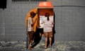 In this photo, two local residents use a landline phone booth in Australia. An orange filter covers the photo.