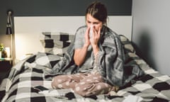 Sick woman with runny nose, sitting in bed.