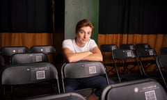 Person in white t-shirt folds arms and leans on back of a chair