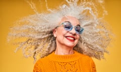 a woman tosses her grey ringlets while smiling broadly