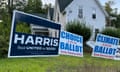 blue sign and two white signs on a lawn in front of house