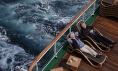 A elderly couple relax in the sun on the rear deck of a cruise liner