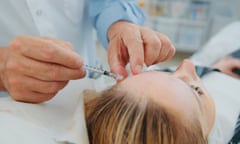 Plastic surgeon doctor making injection botox in woman face under eyebrows on the left side forehead for lifting patient face