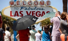 People use umbrellas to block the sun while waiting to take a photo at the "Welcome to Las Vegas" sign Monday, July 8, 2024, in Las Vegas.