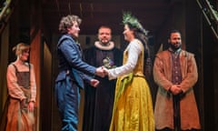 A man and a woman onstage in Jacobean dress face each other holding hands, in front of a priest, as a man and a woman look on