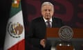 a man in a suit and tie speaks in front of a mexican flag