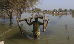 Villagers retrieve belongings, which were they kept on the higher ground surrounded floodwaters, at a village in Sohbat Pur, a flood-hit district of Baluchistan province, Pakistan on 25 October 2022.