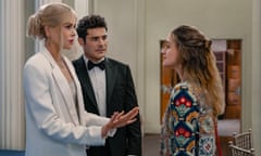 white woman wearing white suit gestures at white woman wearing patterned shirt as a white man wearing a black suit and bowtie looks on