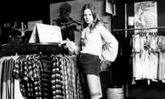 A teenager wearing hot pants and striped knee length socks in a clothes boutique, 1972. 
