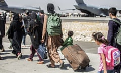 Women and young children pull luggage as they queue to board a plane