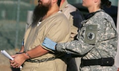 FILE - In this Dec. 6, 2006 file photo, reviewed by a U.S. Dept of Defense official, a shackled detainee is transported by a female guard, front, and male guard, behind, away from his annual Administrative Review Board hearing with U.S. officials, at Camp Delta detention center, Guantanamo Bay U.S. Naval Base, Cuba. A military judge is taking testimony on Friday, Oct. 30, 2015 about female guards at the Guantanamo Bay detention facility in Cuba. (AP Photo/Brennan Linsley, File)