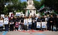 Syrian activists holding placards showing faces of victims of torture