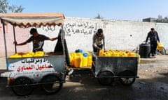 People collect jugs of water from the back of a small truck