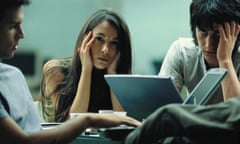 A man and woman looking sad and at a loss, gripping their heads with their laptops open