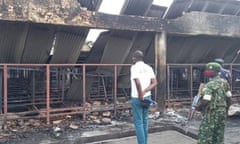 A journalist, police officer and a soldier observe the damage from the fire.