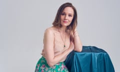 Actor Rachael Stirling sitting leaning on turquoise cloth-covered table, against grey background, May 2024