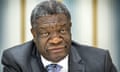 Greying African man wearing a suit jacket, shirt and tie looks at camera