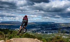 A mountain biker jumps while riding a trail at Bikepark Wales overlooking the town of Merthyr Tydfil and the Brecon Beacons on the horizon.<br>KC3JME A mountain biker jumps while riding a trail at Bikepark Wales overlooking the town of Merthyr Tydfil and the Brecon Beacons on the horizon.