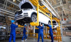 workers lift a car on to the production apparatus