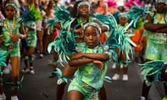 Young people in bright green costumes dance at the Notting hill carnival