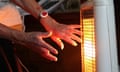 A person warms their hands by a radiator