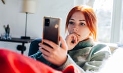 Young woman sitting on couch looking at mobile phone