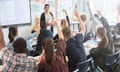 Teenage schoolchildren raise their hands in class