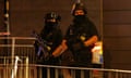 Armed police officers stand next to a police cordon outside the Manchester Arena.