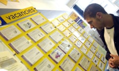A man looking hopfeully at a lemon yellow vacancies board in a jobcentre