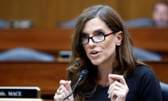 woman wearing glasses gestures and speaks in front of microphone