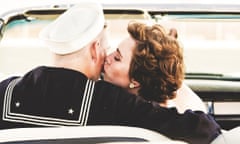 Young woman kissing sailor in convertible car.
