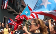 Protesters Demand Resignation Of Puerto Rico's Governor Ricardo Rossello<br>SAN JUAN, PUERTO RICO - JULY 24: Brian Hernandez waves a Puerto Rican flag from a top a police barricade on a street leading to the Governor's Mansion, as reports persist that Ricardo Rossello, the Governor of Puerto Rico, will step down on July 24, 2019 in Old San Juan, Puerto Rico. Protesters have been calling on Gov. Rosselló to step down after a group chat was exposed that included misogynistic and homophobic comments (Photo by Joe Raedle/Getty Images)