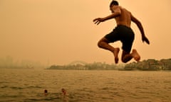 A swimmer jumps in the water as smoke haze from bushfires in New South Wales blankets Sydney, Australia, 19 December 2019.